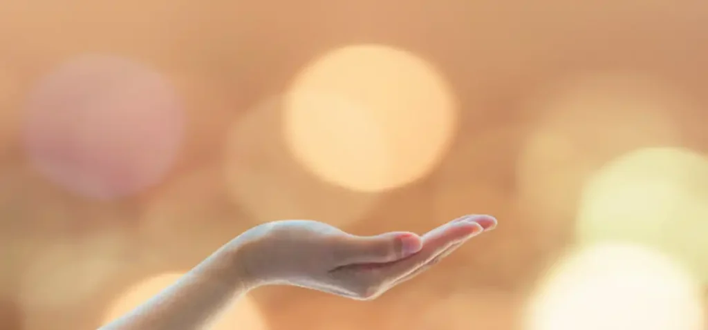 A hand is holding out its palm in front of the sun.