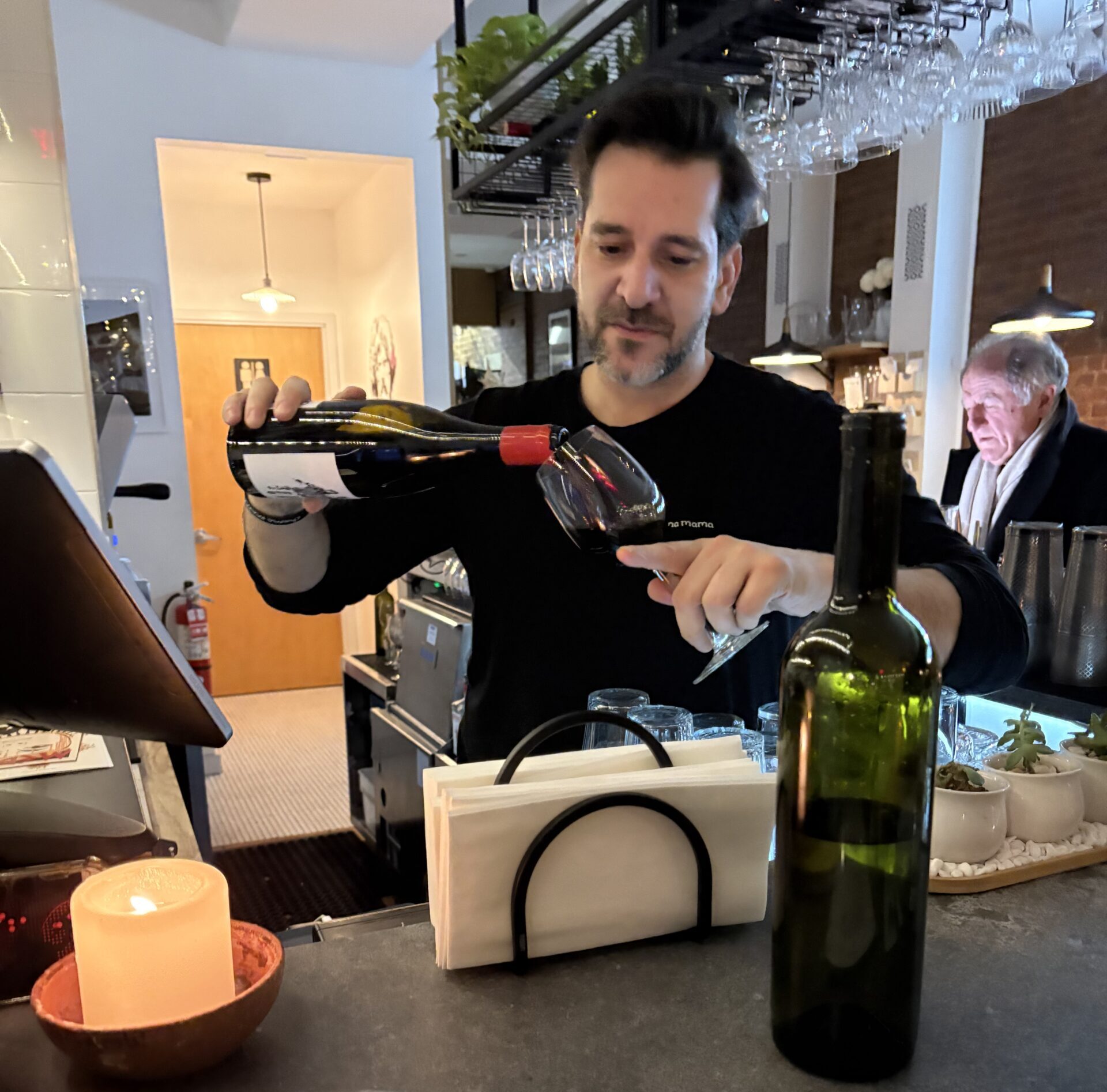 Man pouring wine at a bar counter.